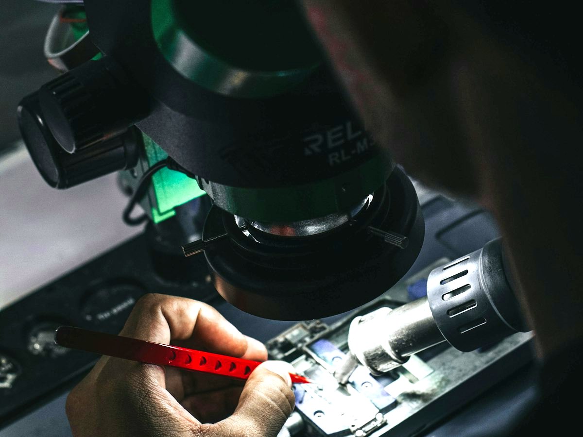 Técnico trabajando bajo el microscopio sobre la tarjeta de un celular